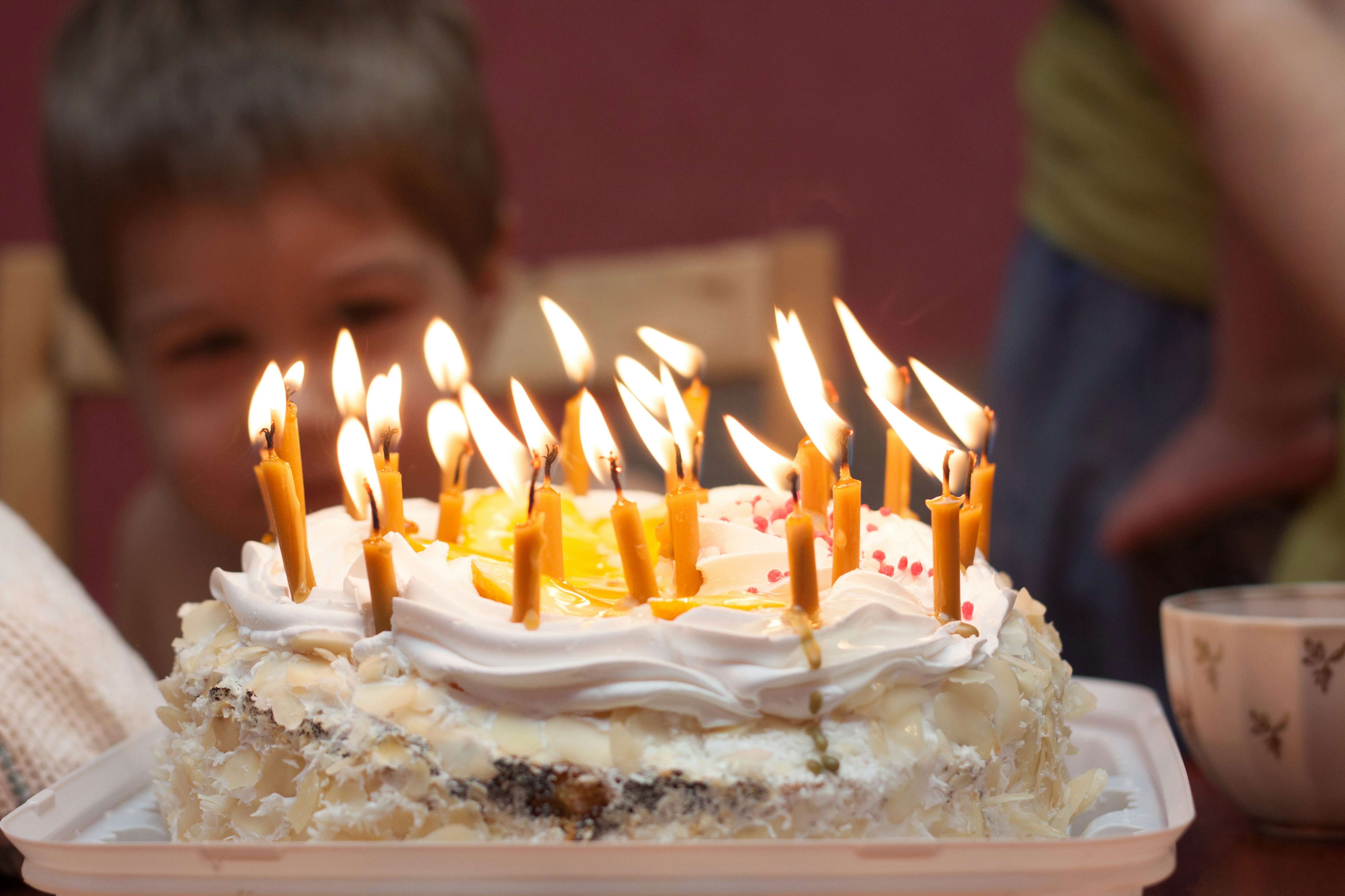 A young boy sitting in front of a birthday cake with lit candles photo ...
