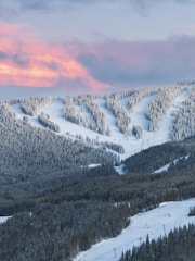 A mountain covered in snow with a pink sky in the background