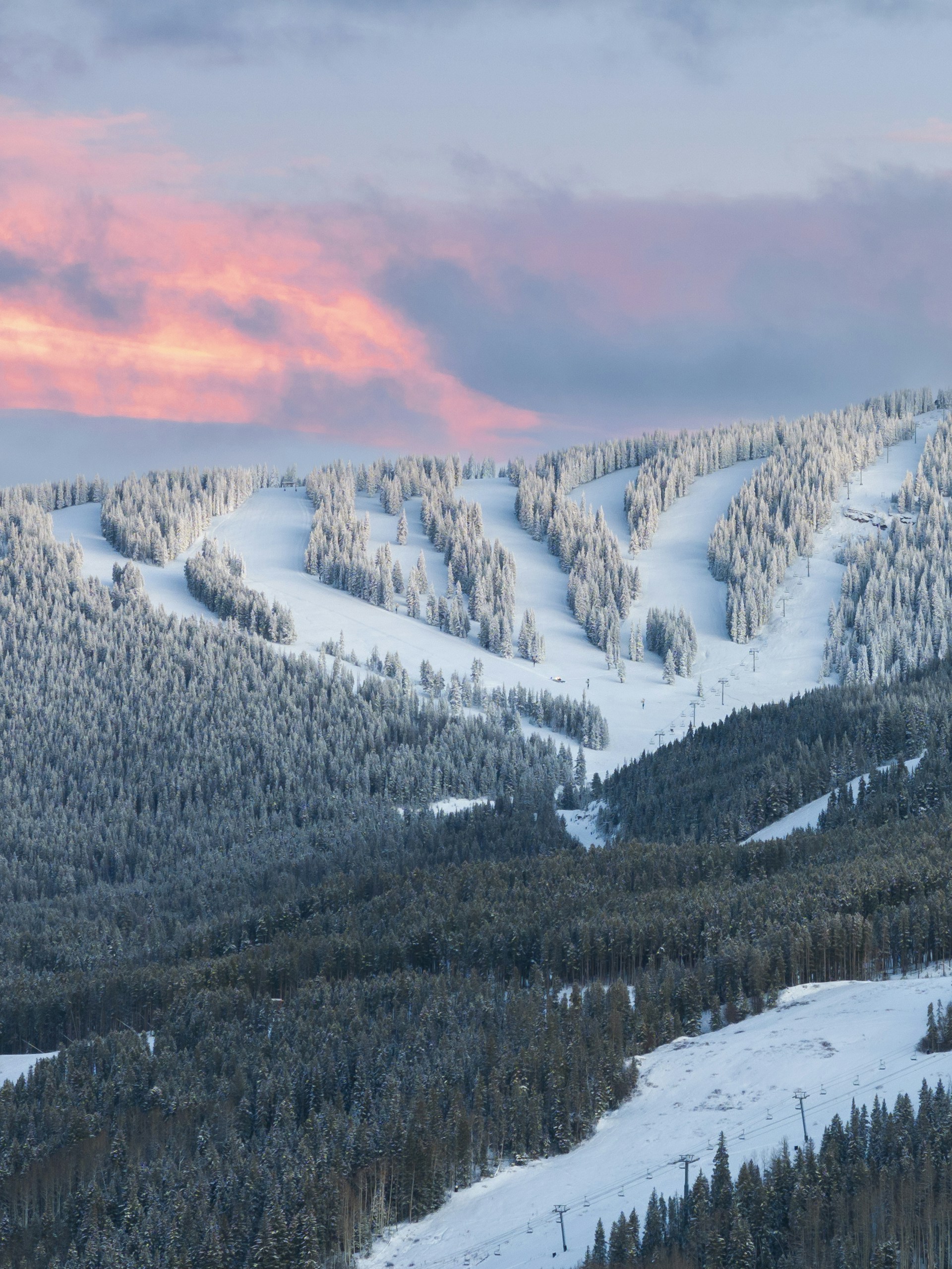 A mountain covered in snow with a pink sky in the background