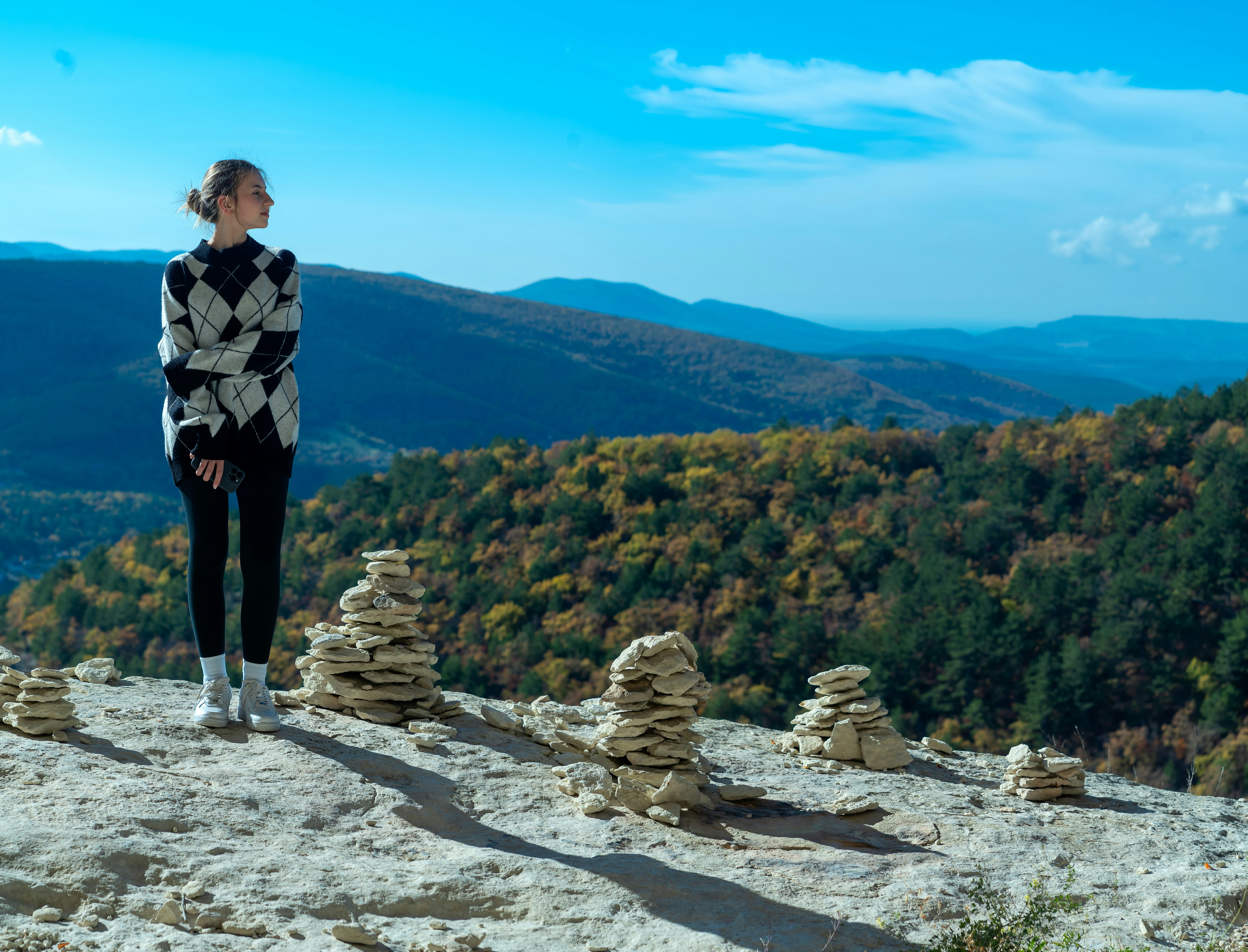 A woman standing on top of a rock covered hillside