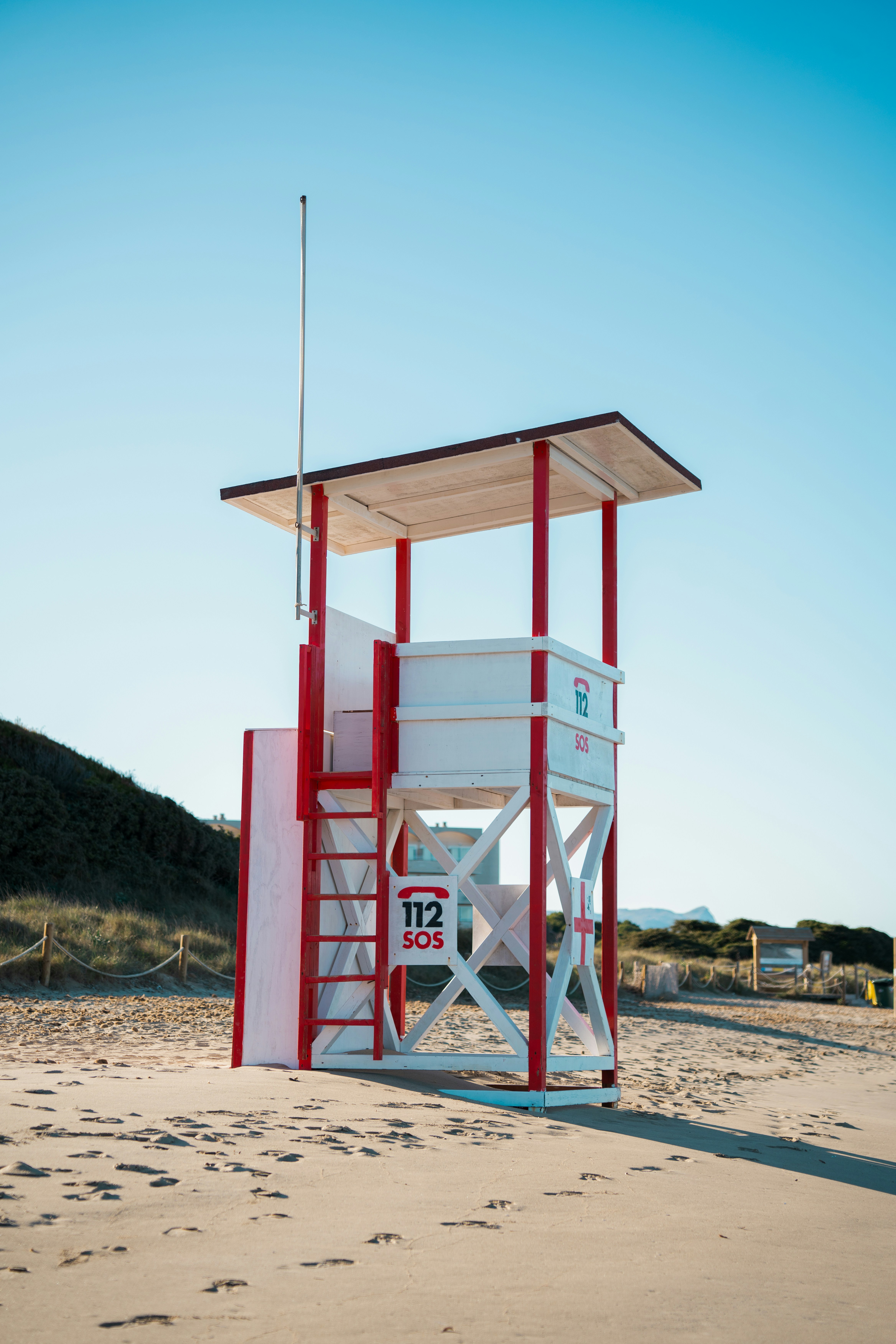 A red and white lifeguard stand on the beach
