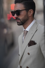 A man in a suit and sunglasses standing next to a pole
