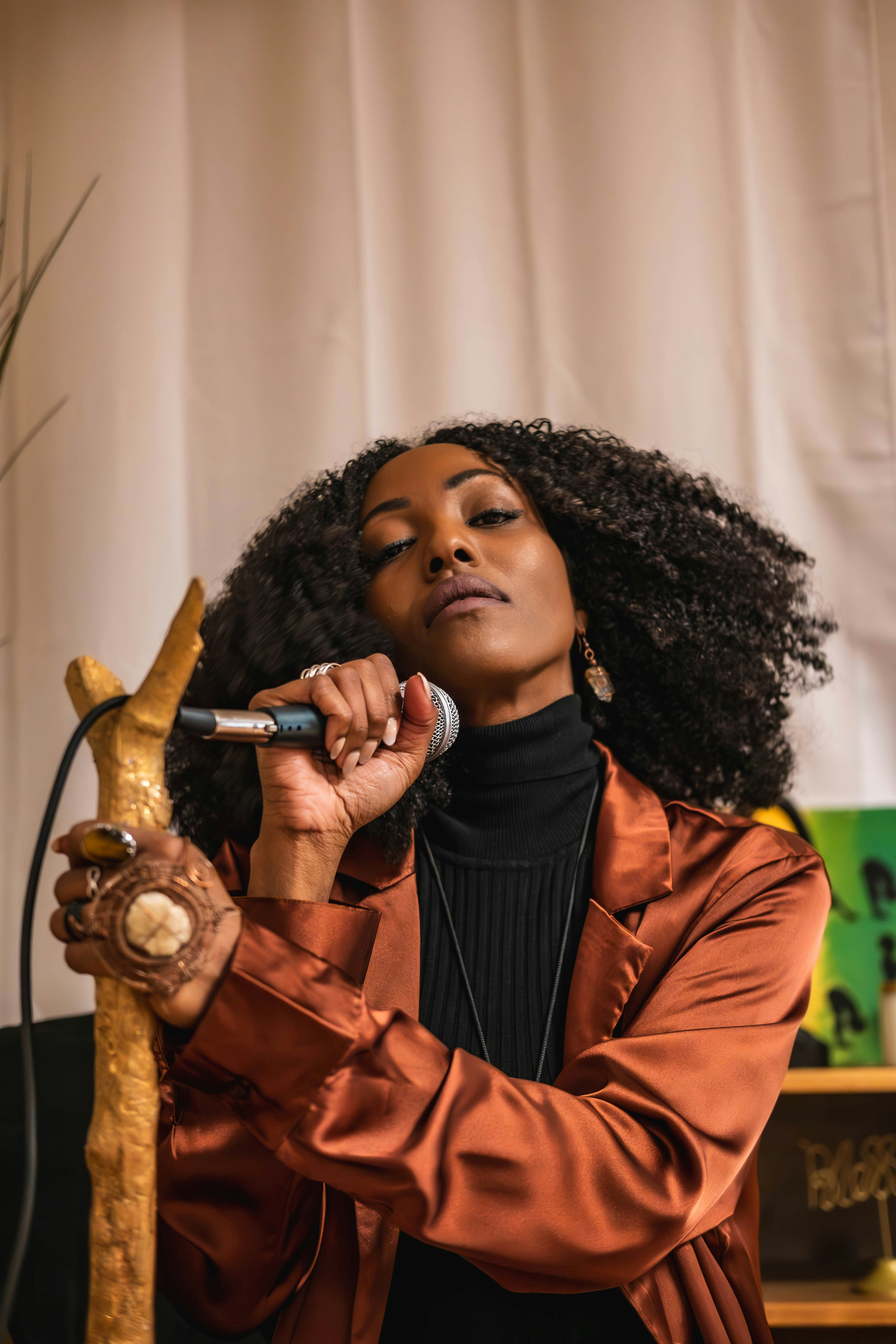 A woman in a brown jacket holding a microphone