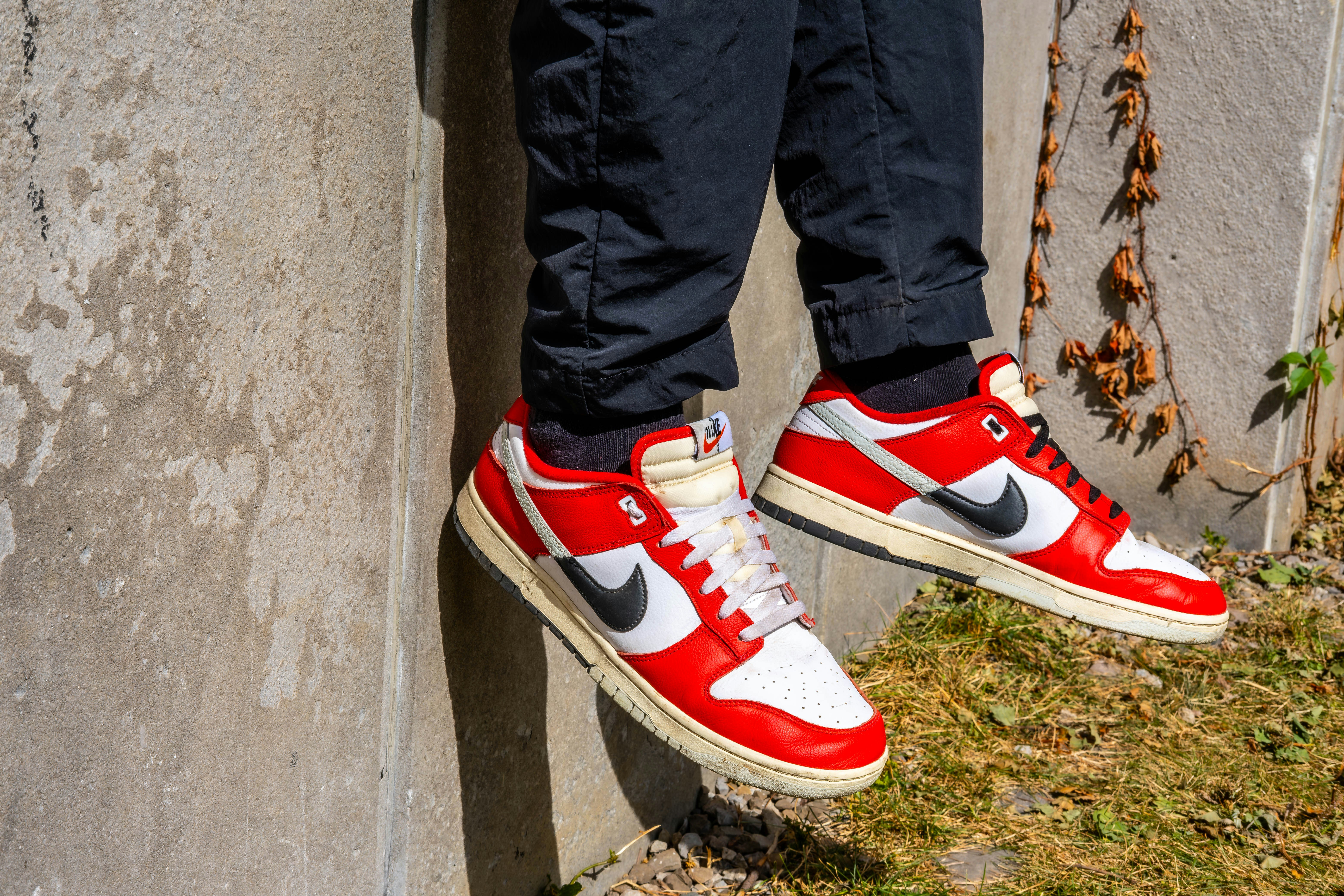 A pair of red and white sneakers hanging off the side of a building