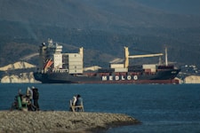 A group of people sitting on a rock next to a body of water