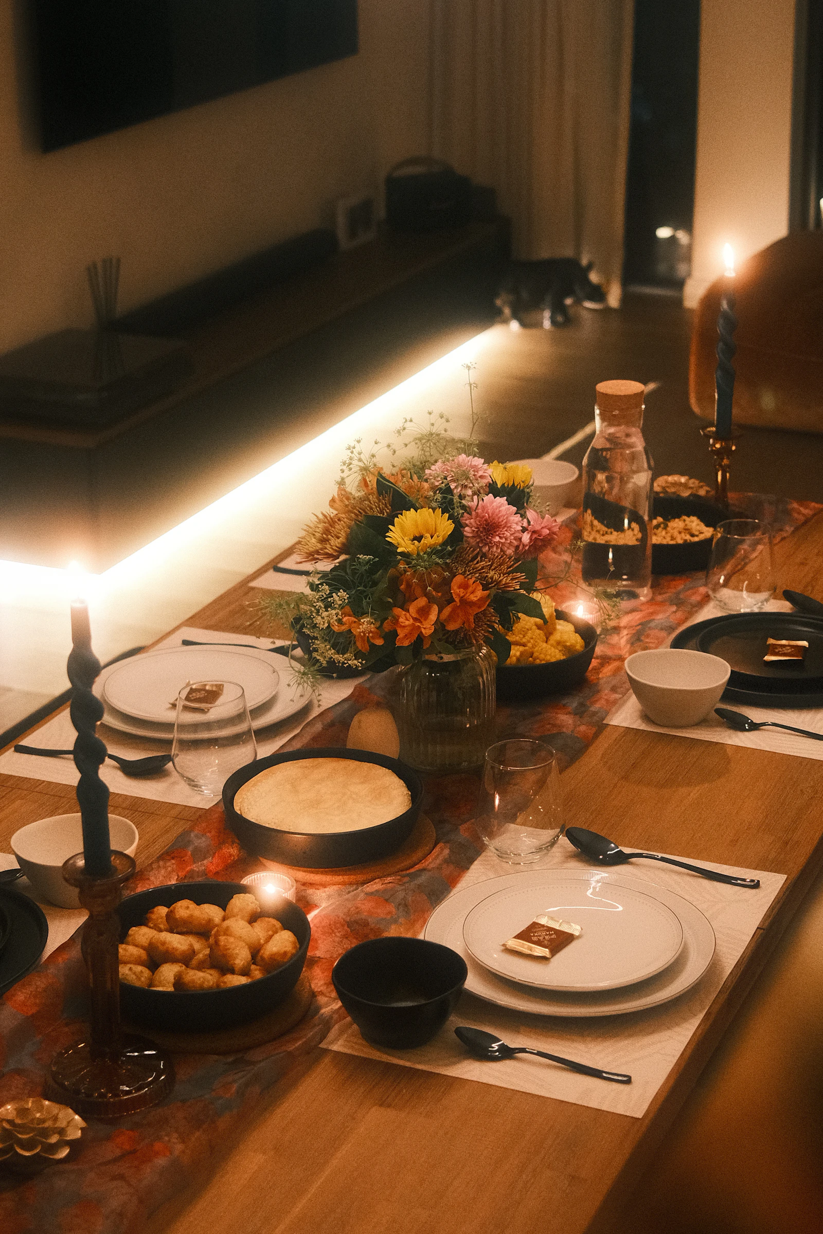 A candlelit table styled with flowers against a moody, dark backdrop
