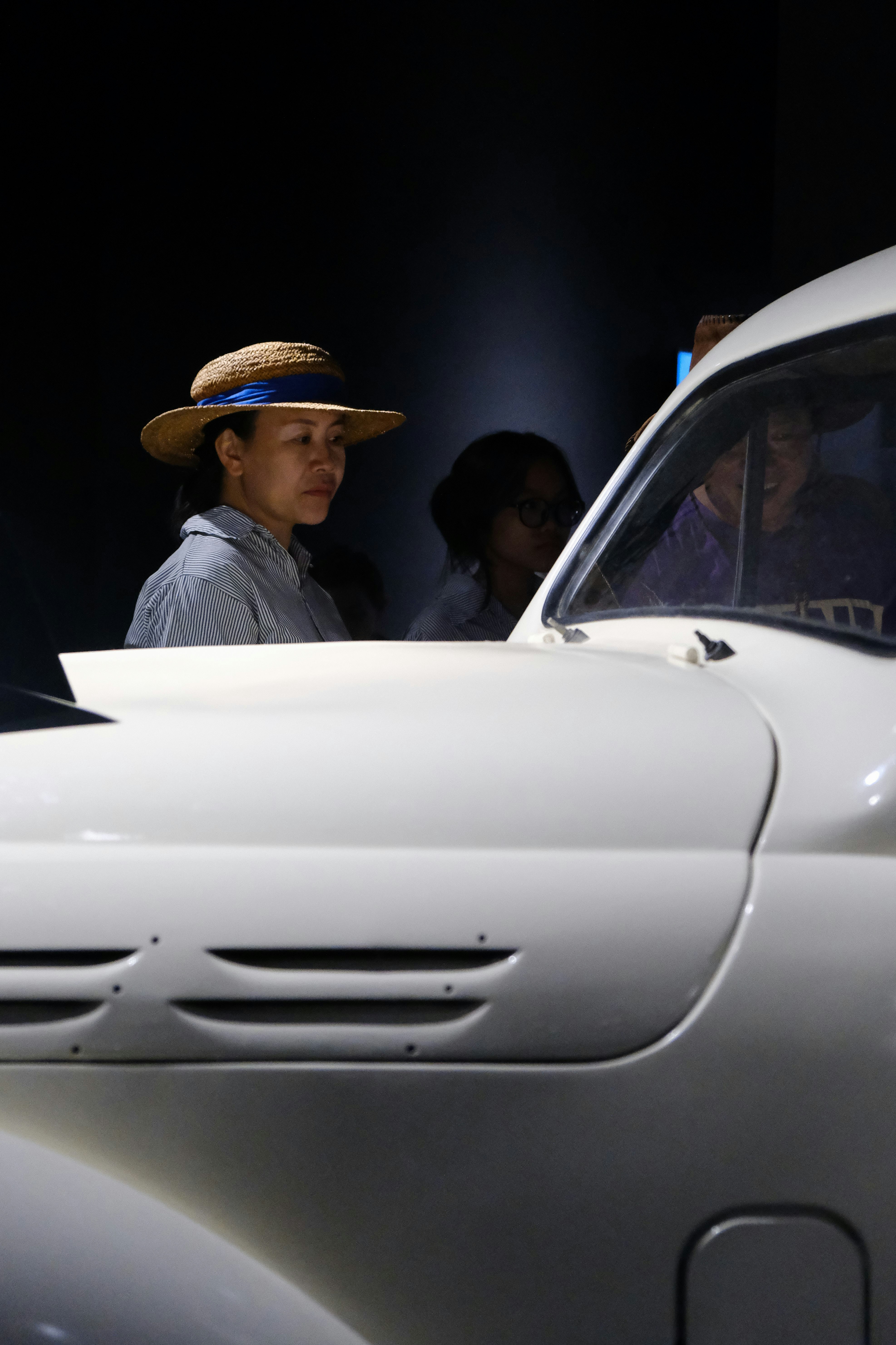 A man in a hat standing next to a white car