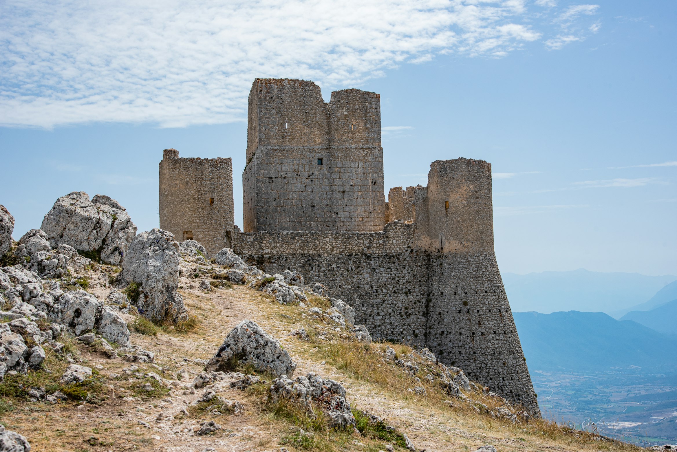 Stone castle sitting on top of a mountain