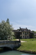 A bridge over a river in front of a large house