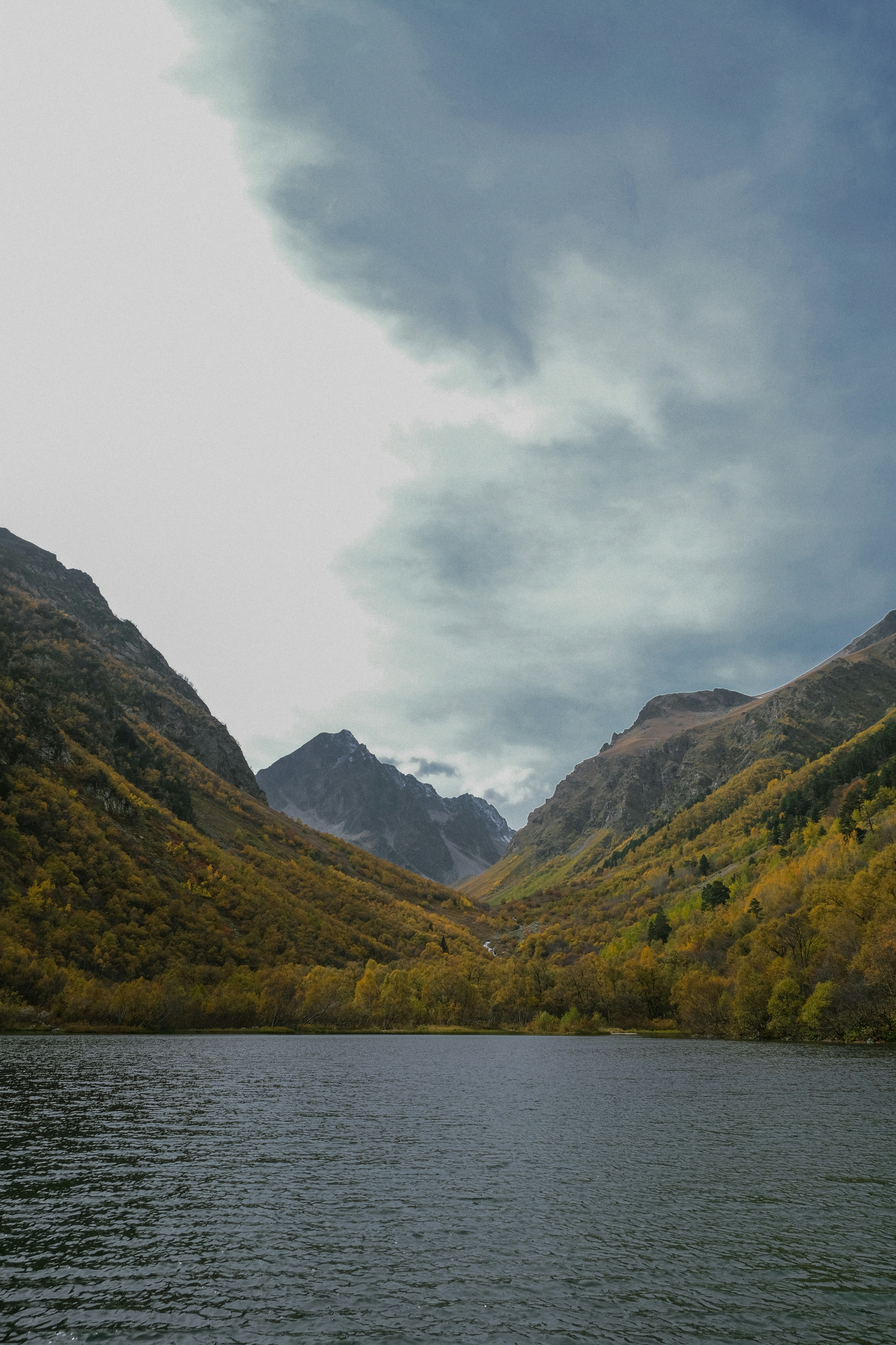 A body of water surrounded by mountains under a cloudy sky