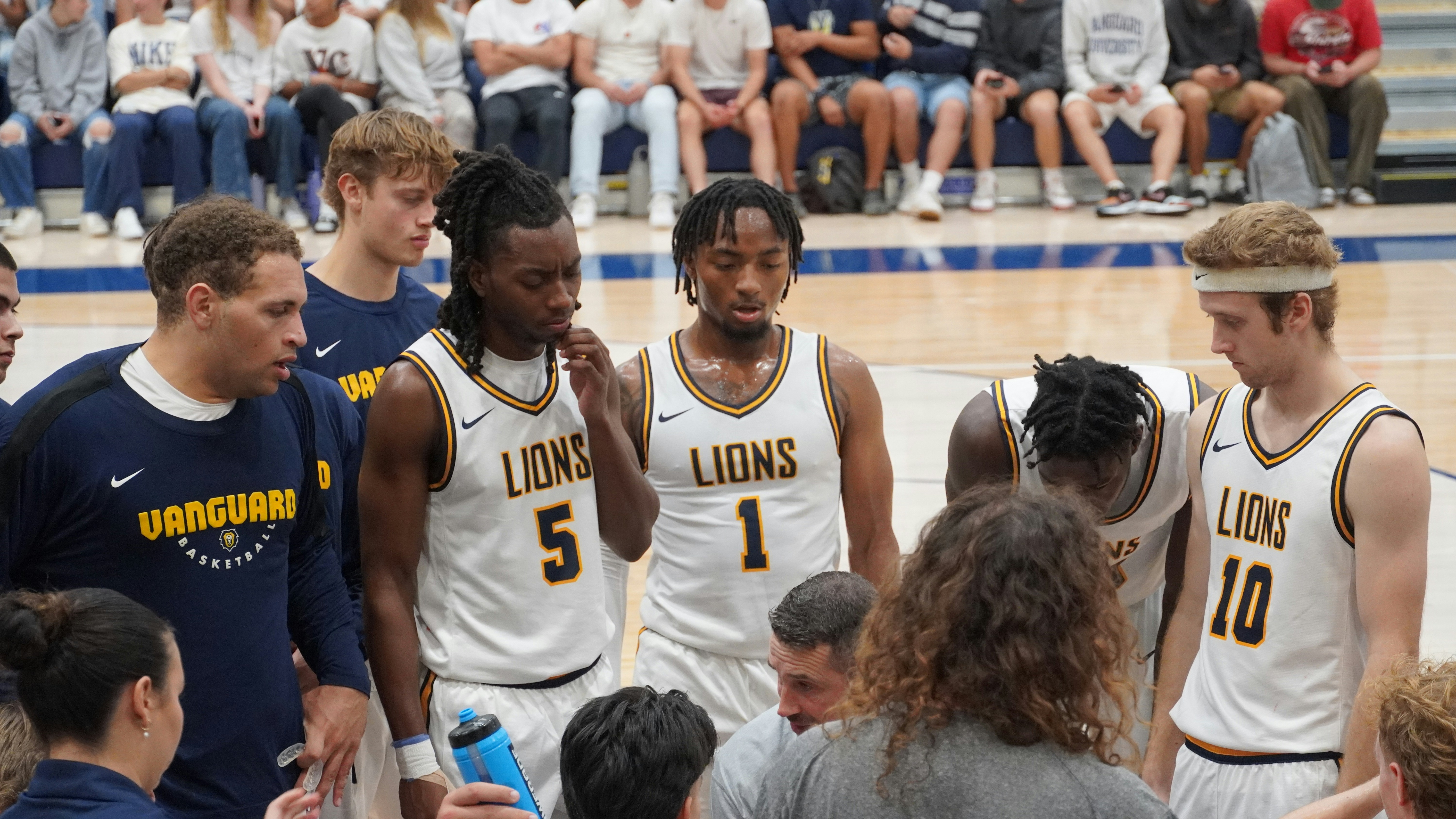 Basketball team huddle with coach giving tactical instructions, indoor court