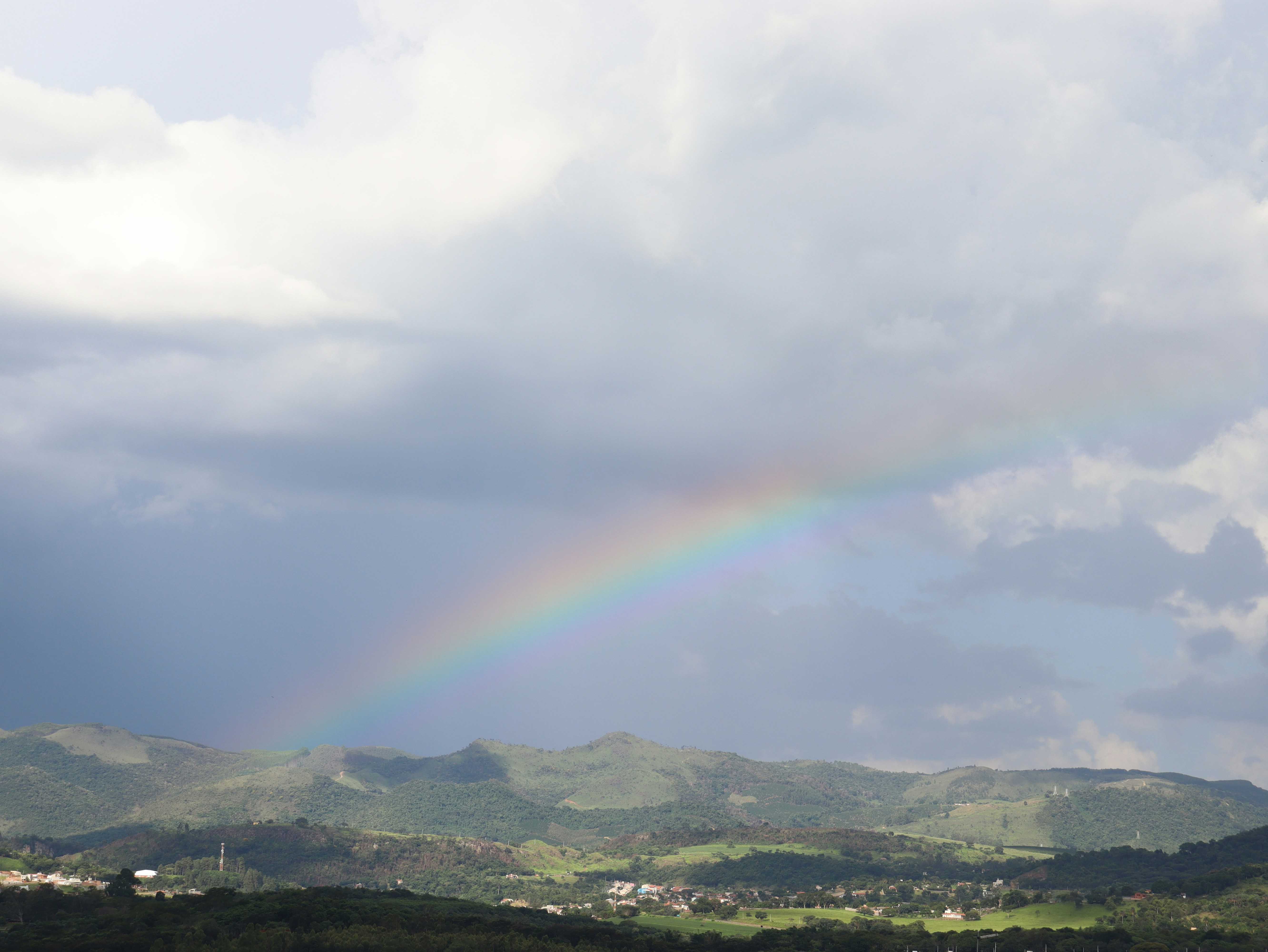 A rainbow in a cloudy sky over a valley