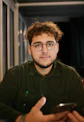 A man with glasses is looking at a cell phone