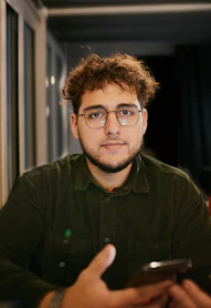 A man with glasses is looking at a cell phone