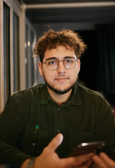 A man with glasses is looking at a cell phone