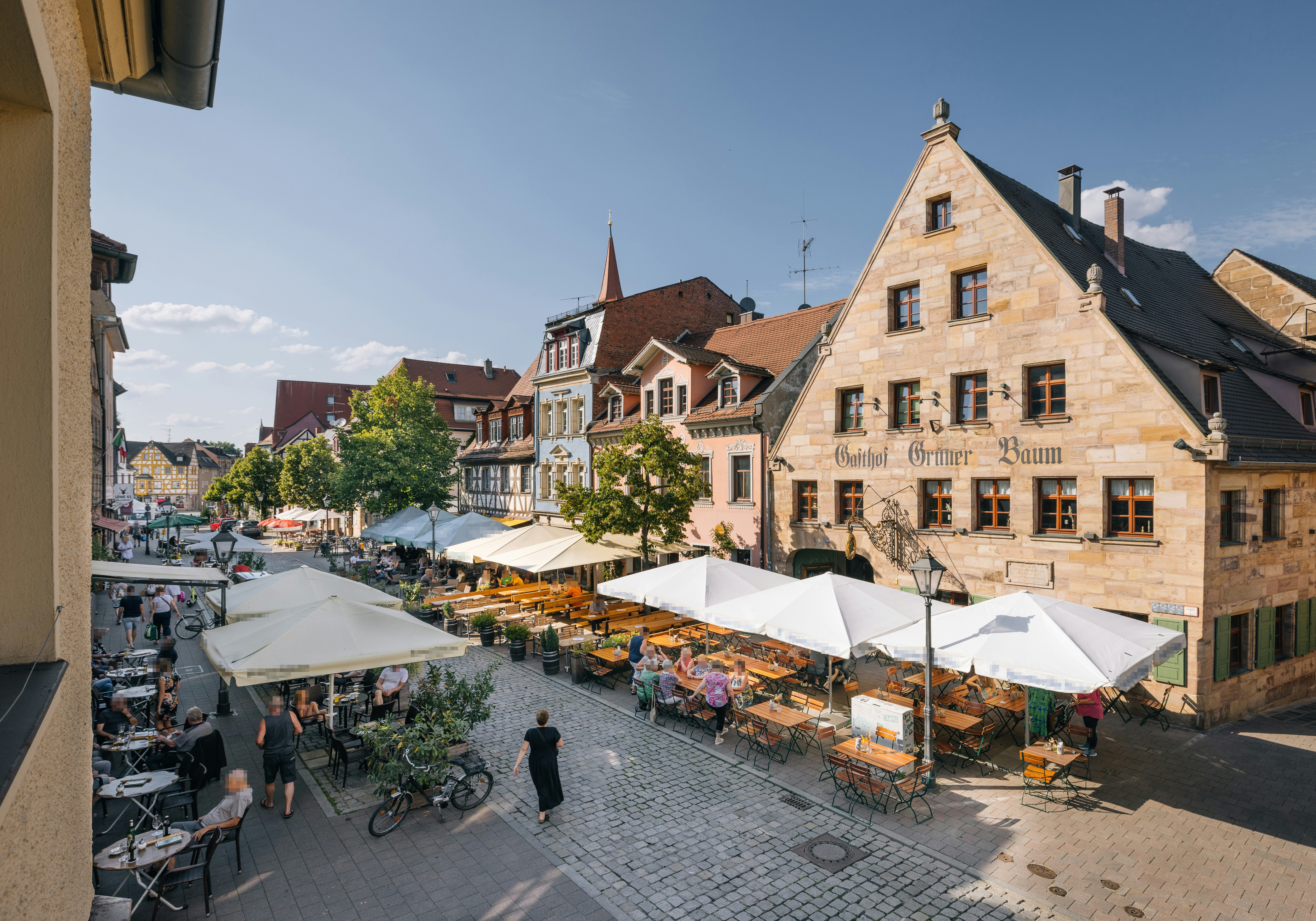 A town square with tables and umbrellas on a sunny day