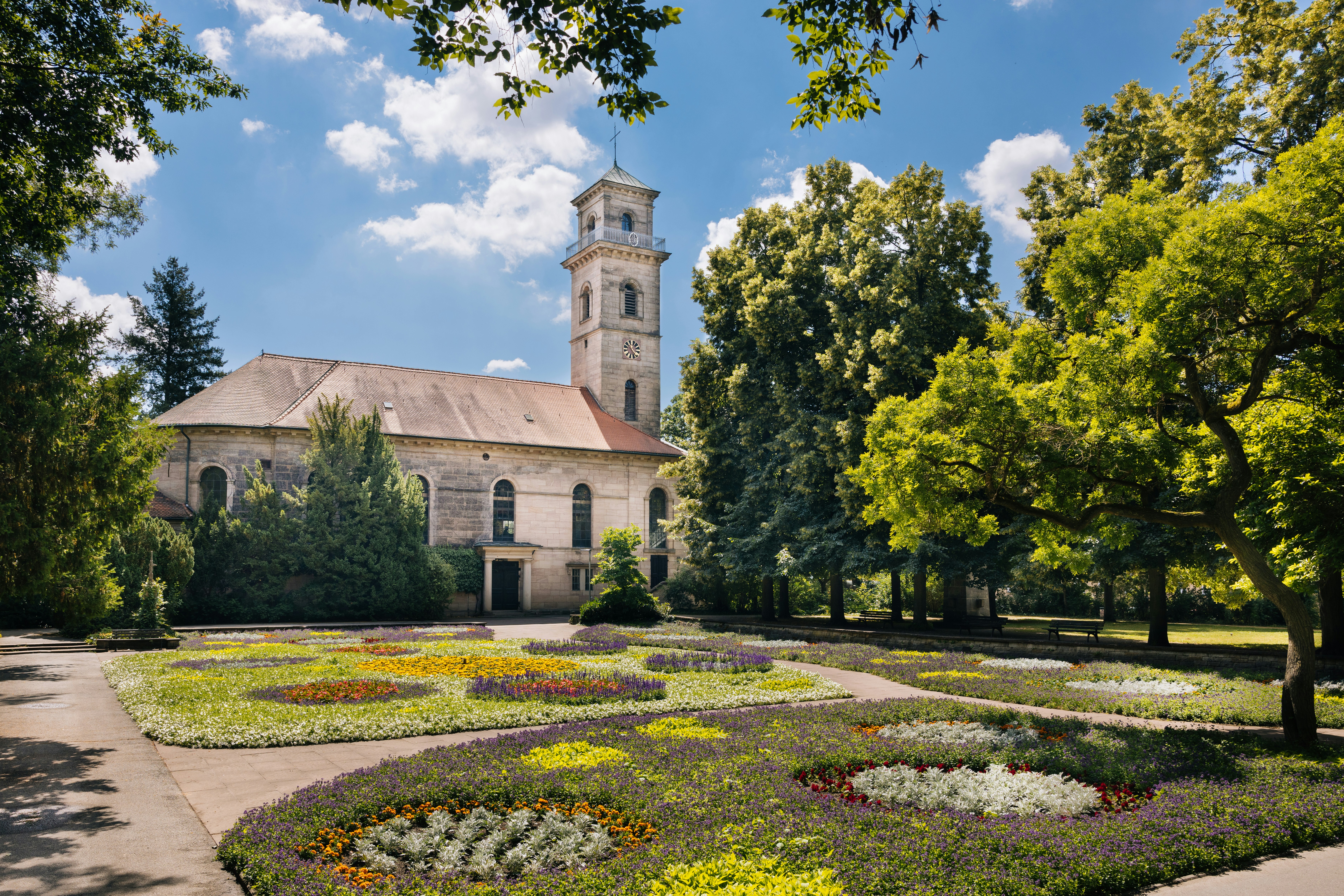 A building with a clock tower in the middle of a garden