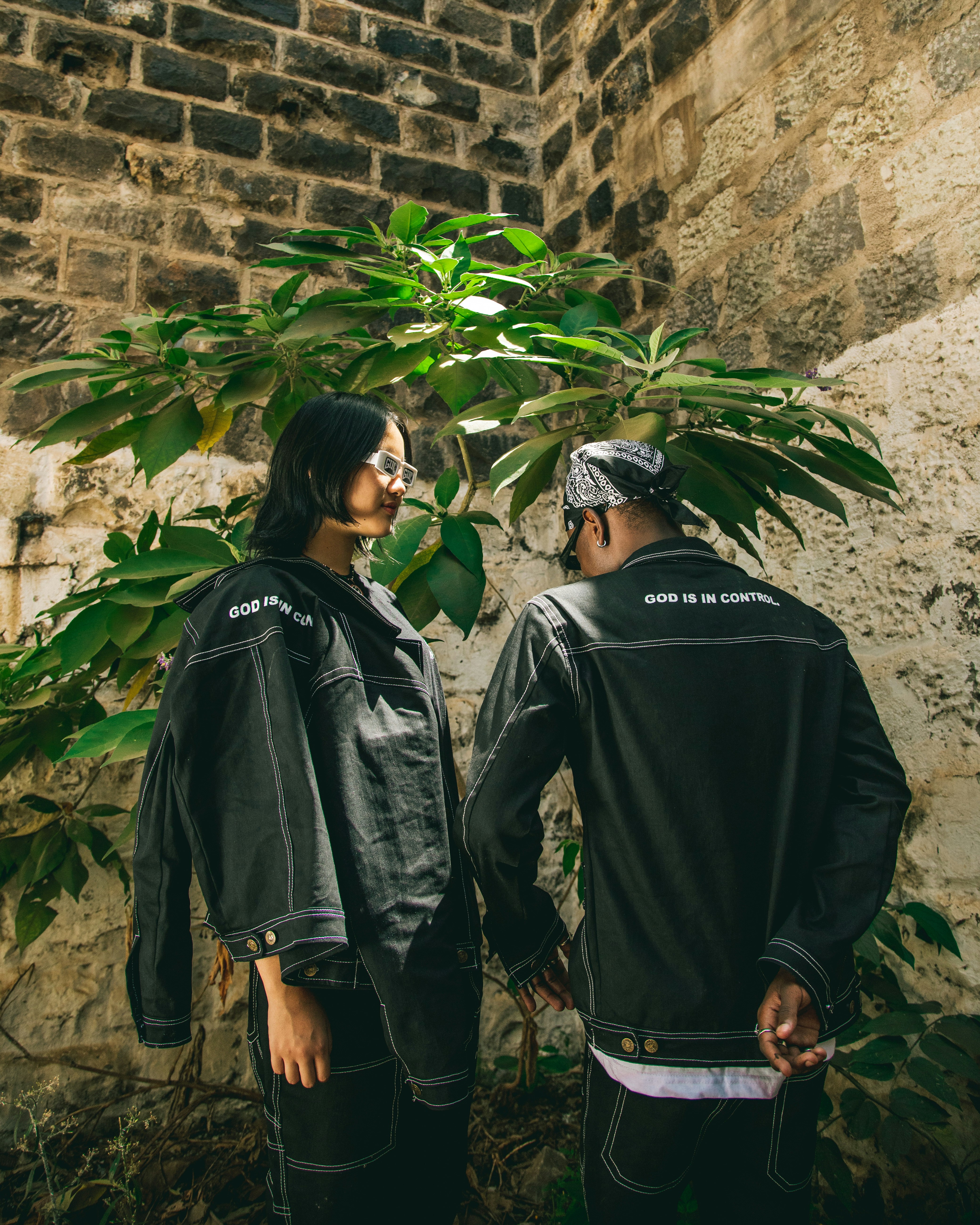 Two people standing next to each other near a tree