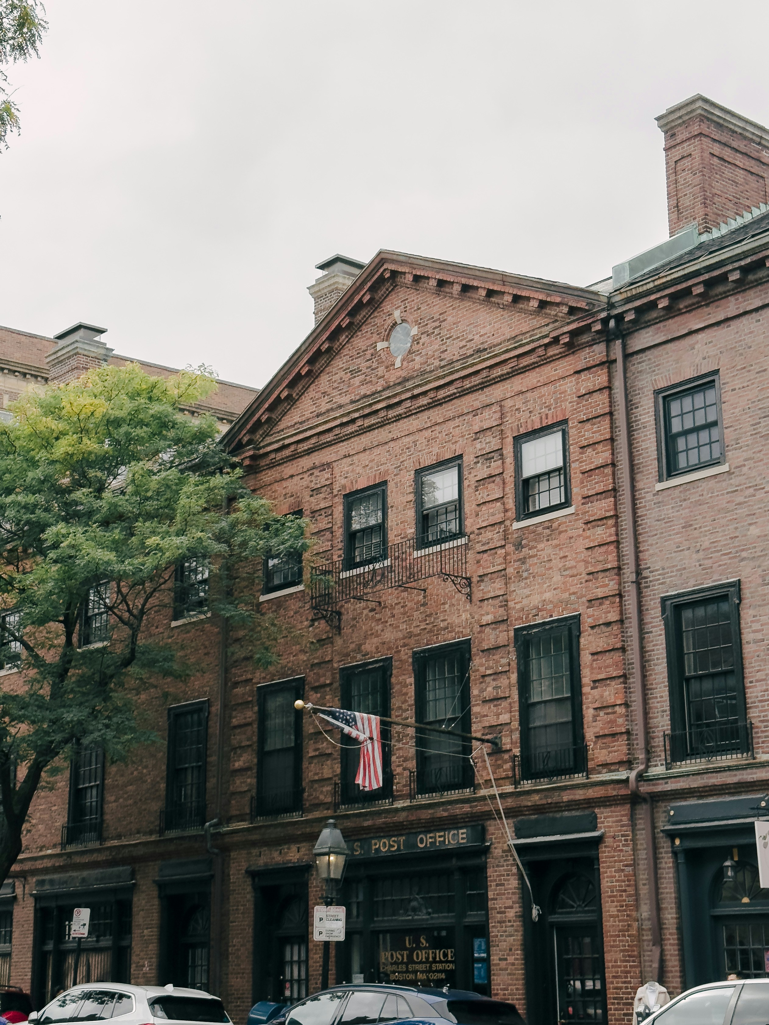 A row of brick buildings with cars parked in front of them