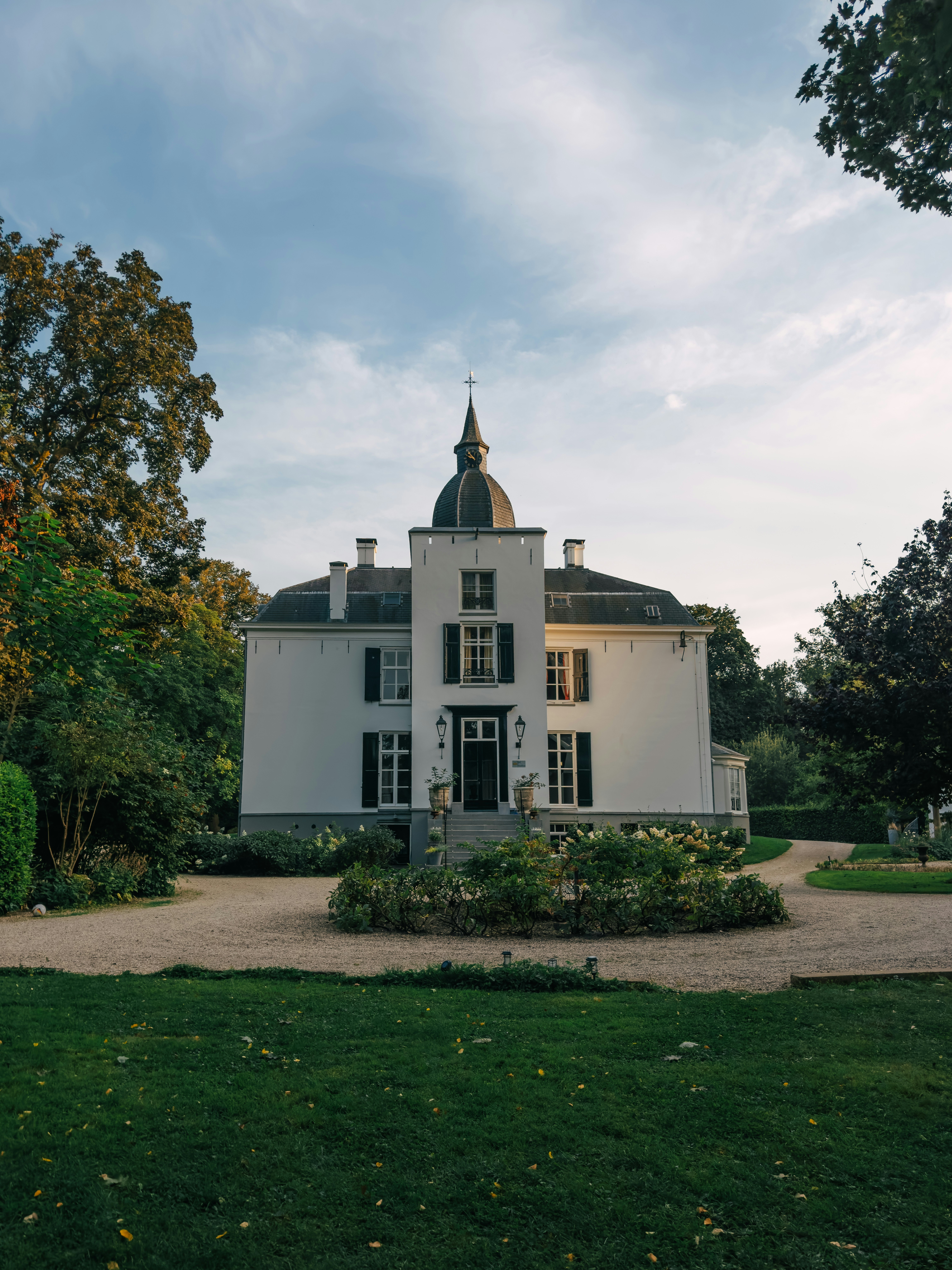 A large white house sitting in the middle of a lush green field