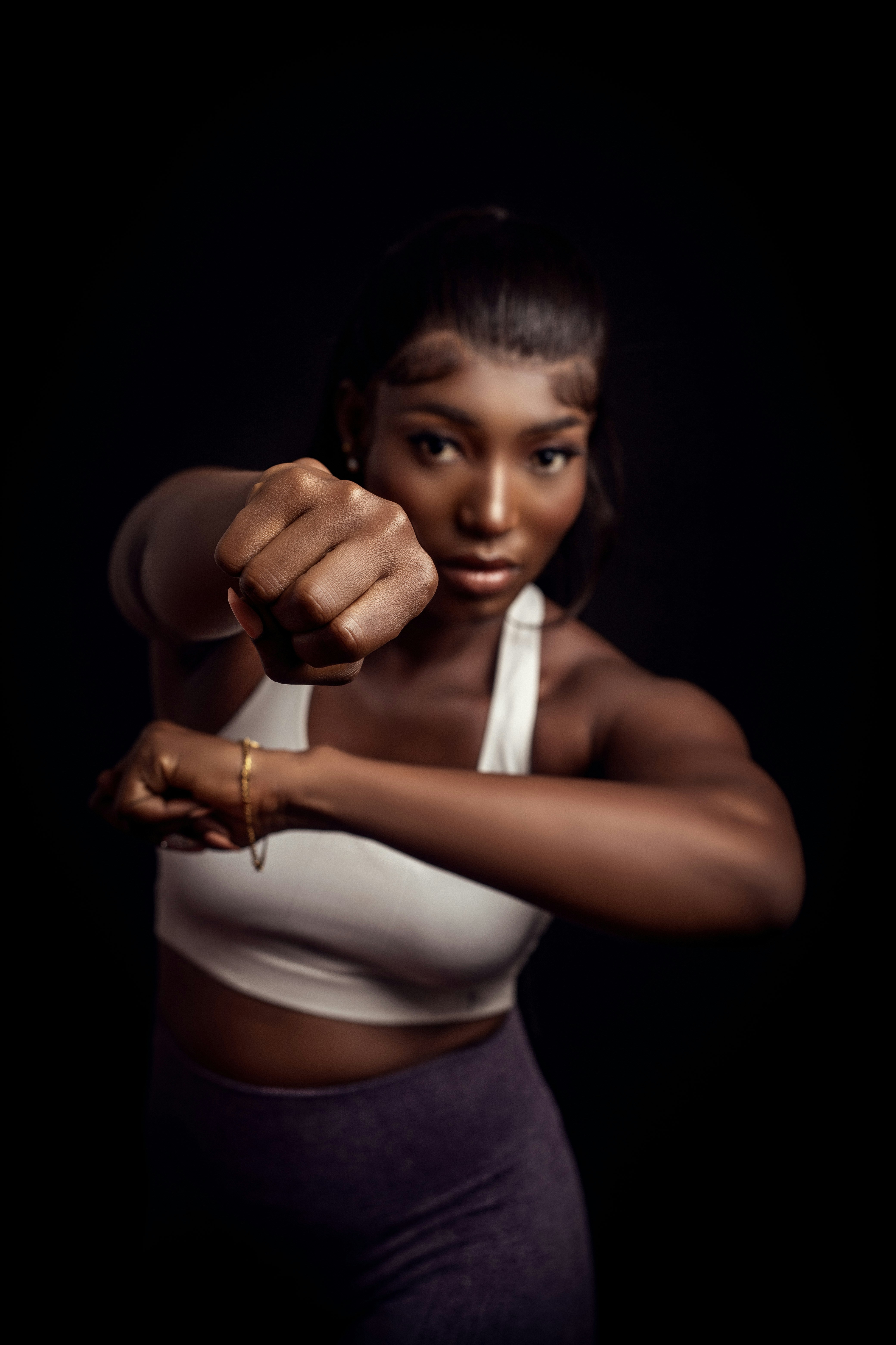 A woman in a white tank top pointing a gun at the camera
