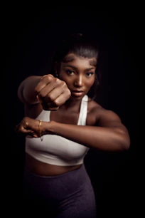 A woman in a white tank top pointing a gun at the camera