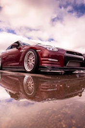 A red sports car sitting on top of a reflective surface