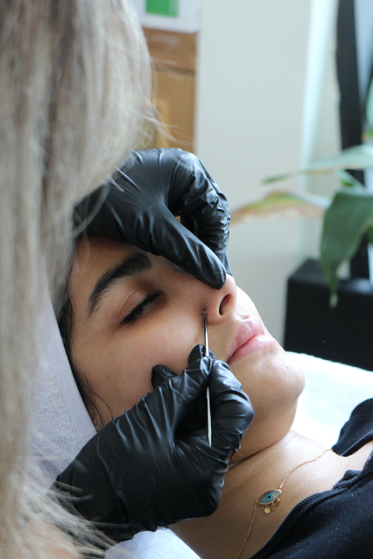 Esteticista con guantes valorando la piel de una clienta antes de una micropigmentación