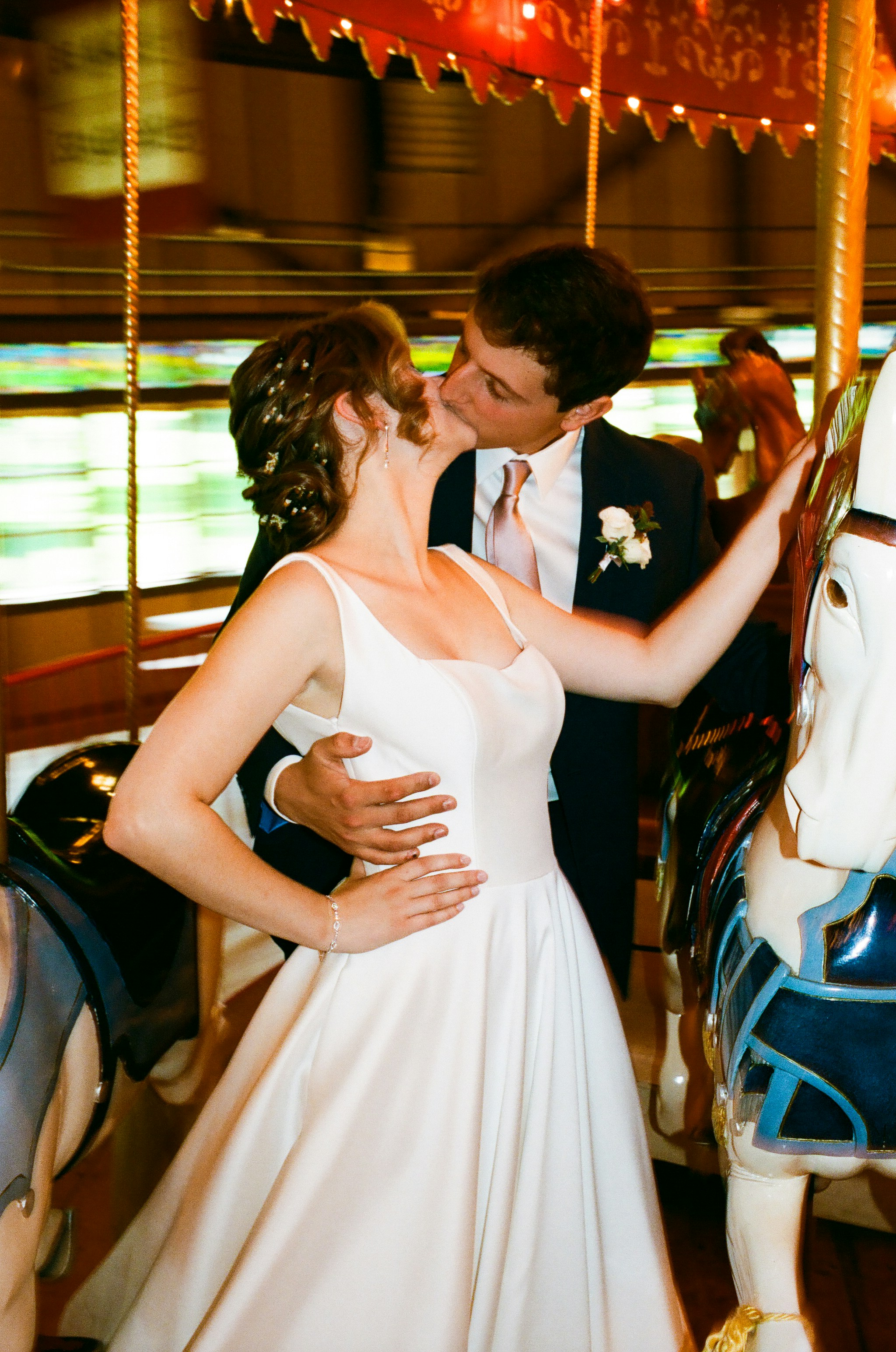 A bride and groom kissing on a merry go round