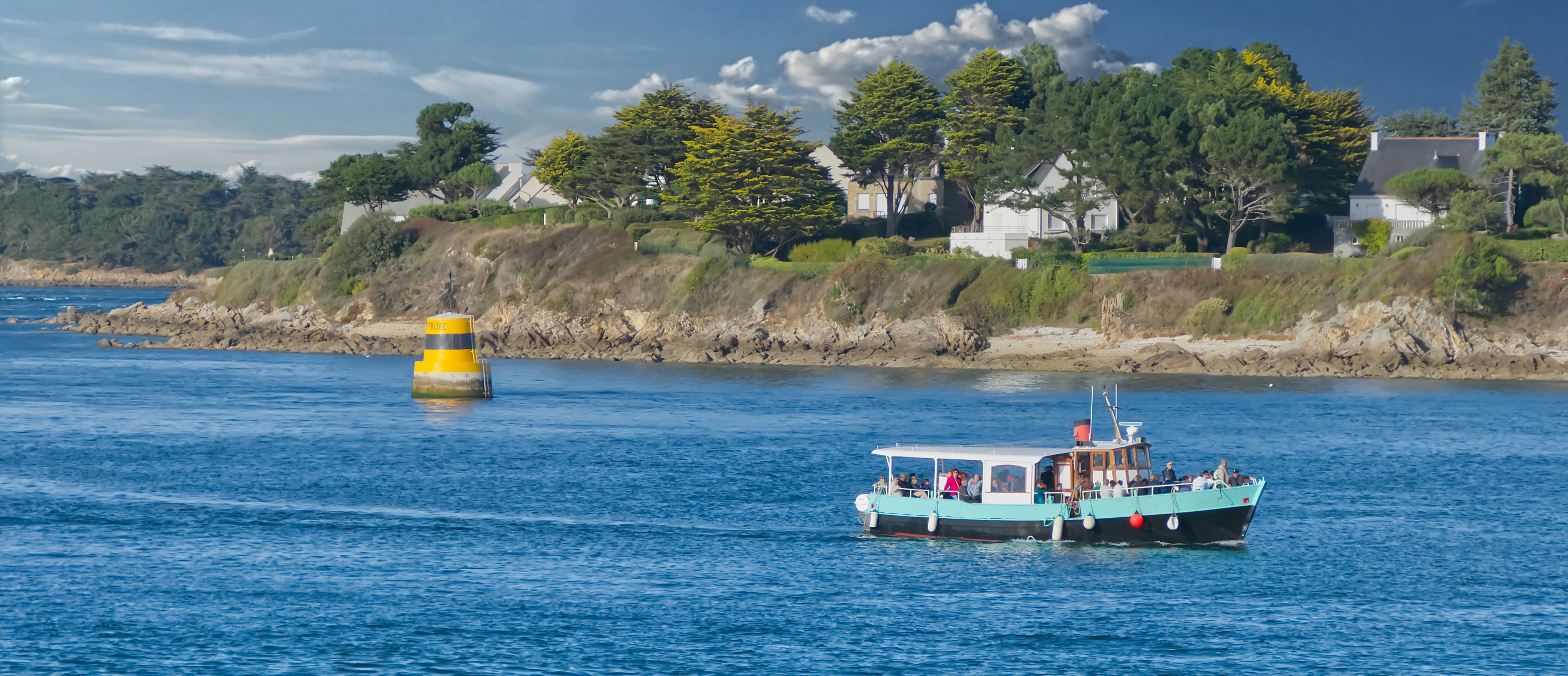 A boat traveling down a river next to a lush green hillside
