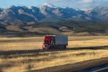 A red semi truck driving down a rural road