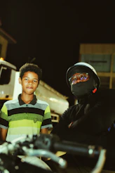 A man standing next to a boy on a motorcycle