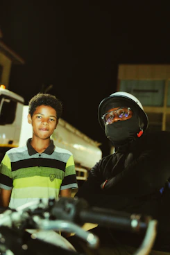 A man standing next to a boy on a motorcycle