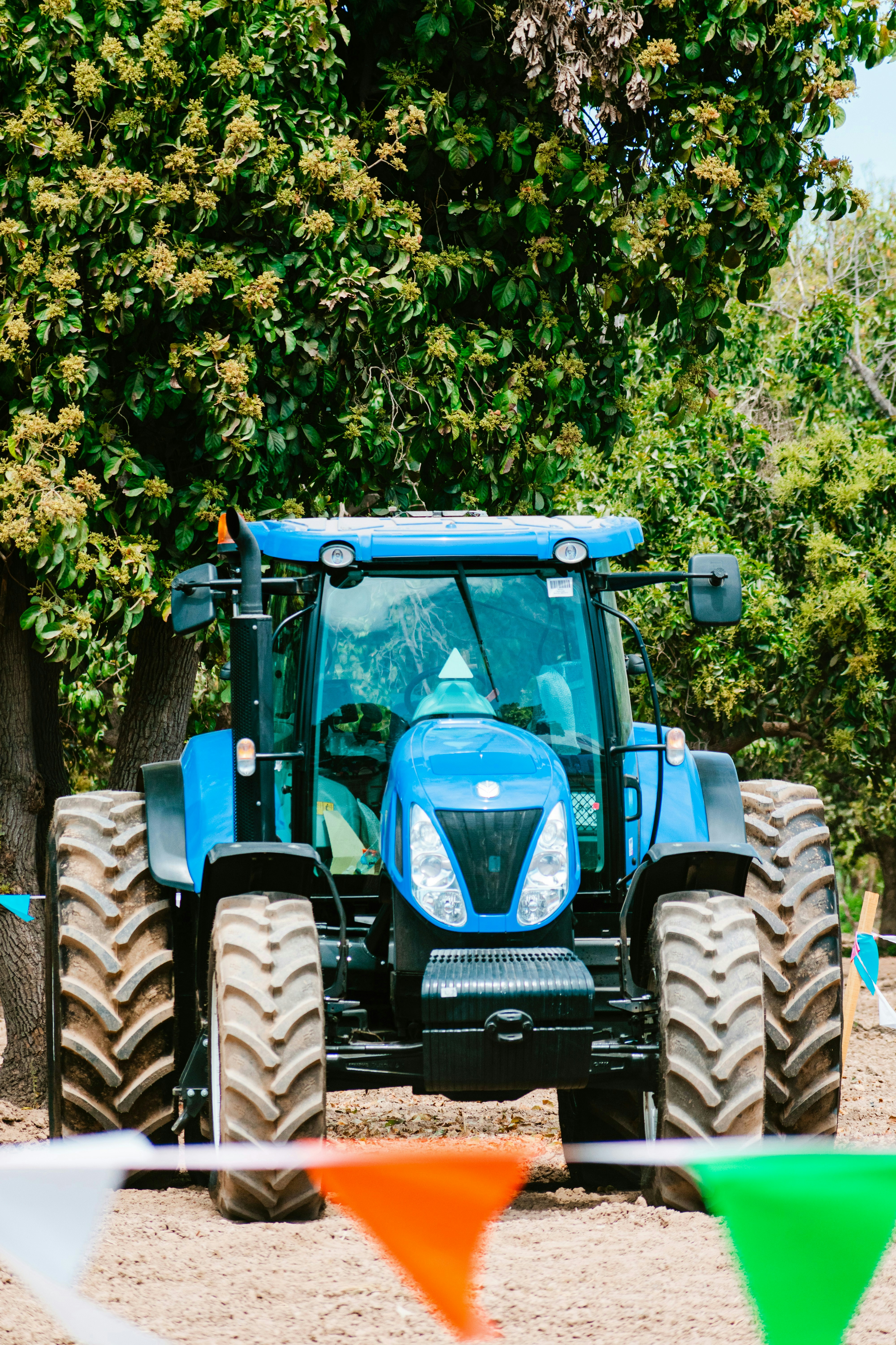 A blue tractor parked in a field with trees in the background