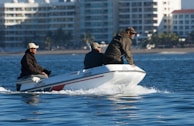 A couple of men riding on the back of a white boat
