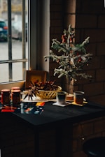 A small christmas tree sits on a table in front of a window