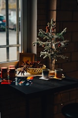 A small christmas tree sits on a table in front of a window