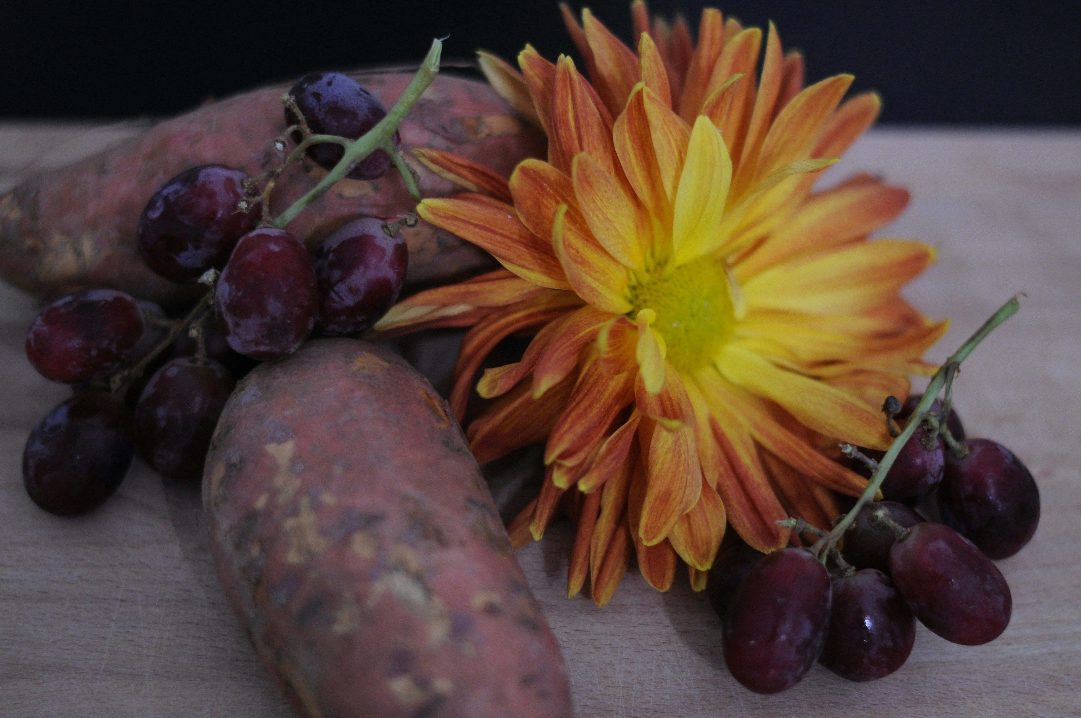 A bunch of grapes and a flower on a cutting board