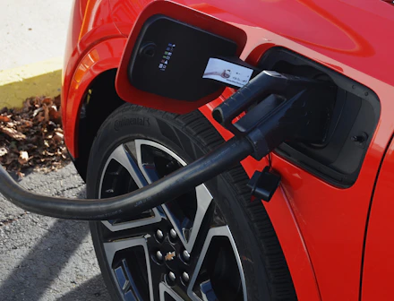 A red car with a charger hooked up to it