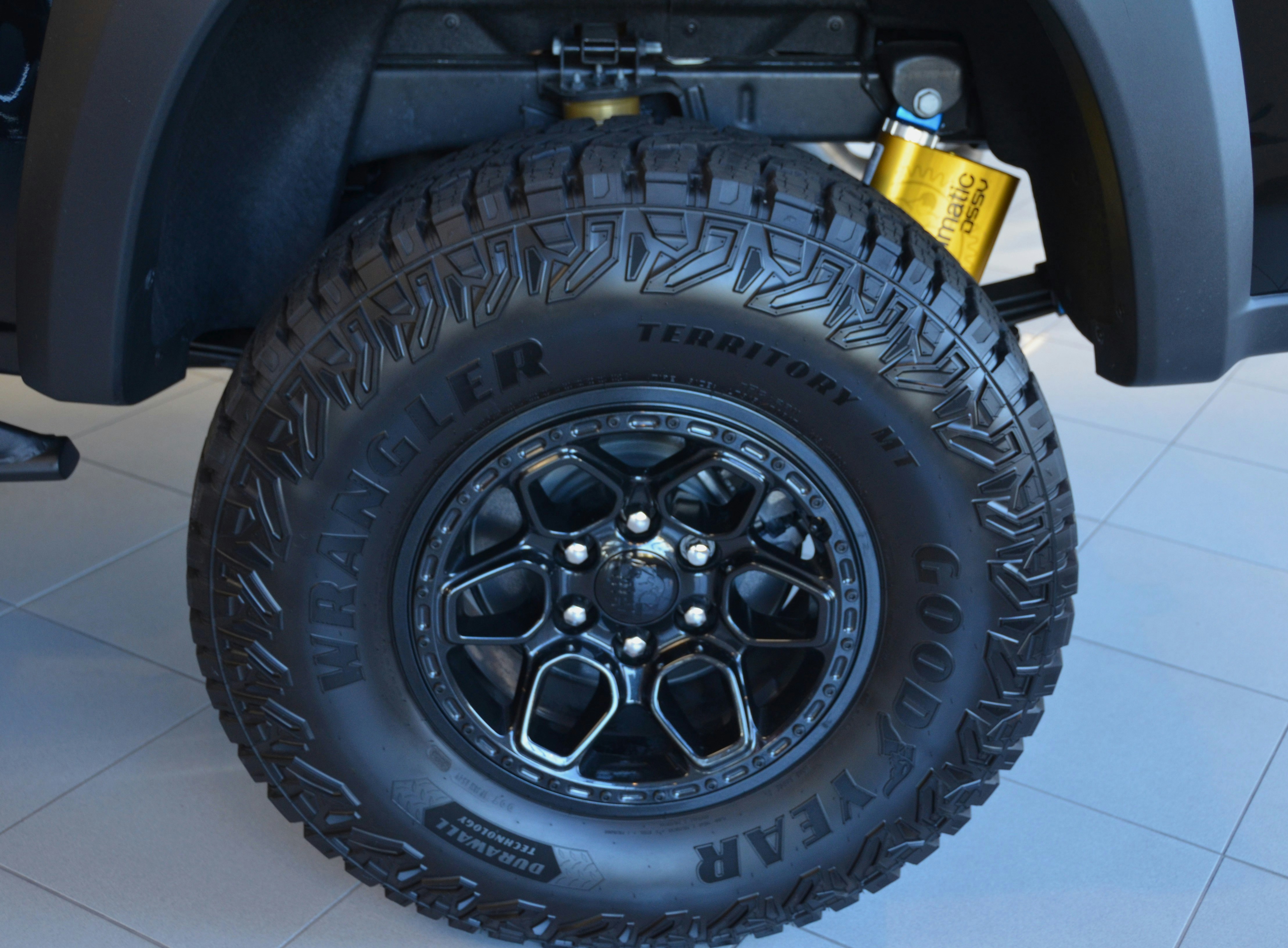 EV owner checking tire tread depth on a parked electric car in a driveway