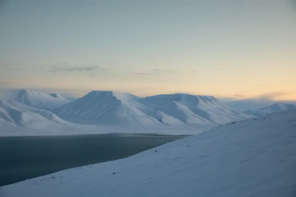 Snow-covered mountains under a pale sky — Svalbard, Norway