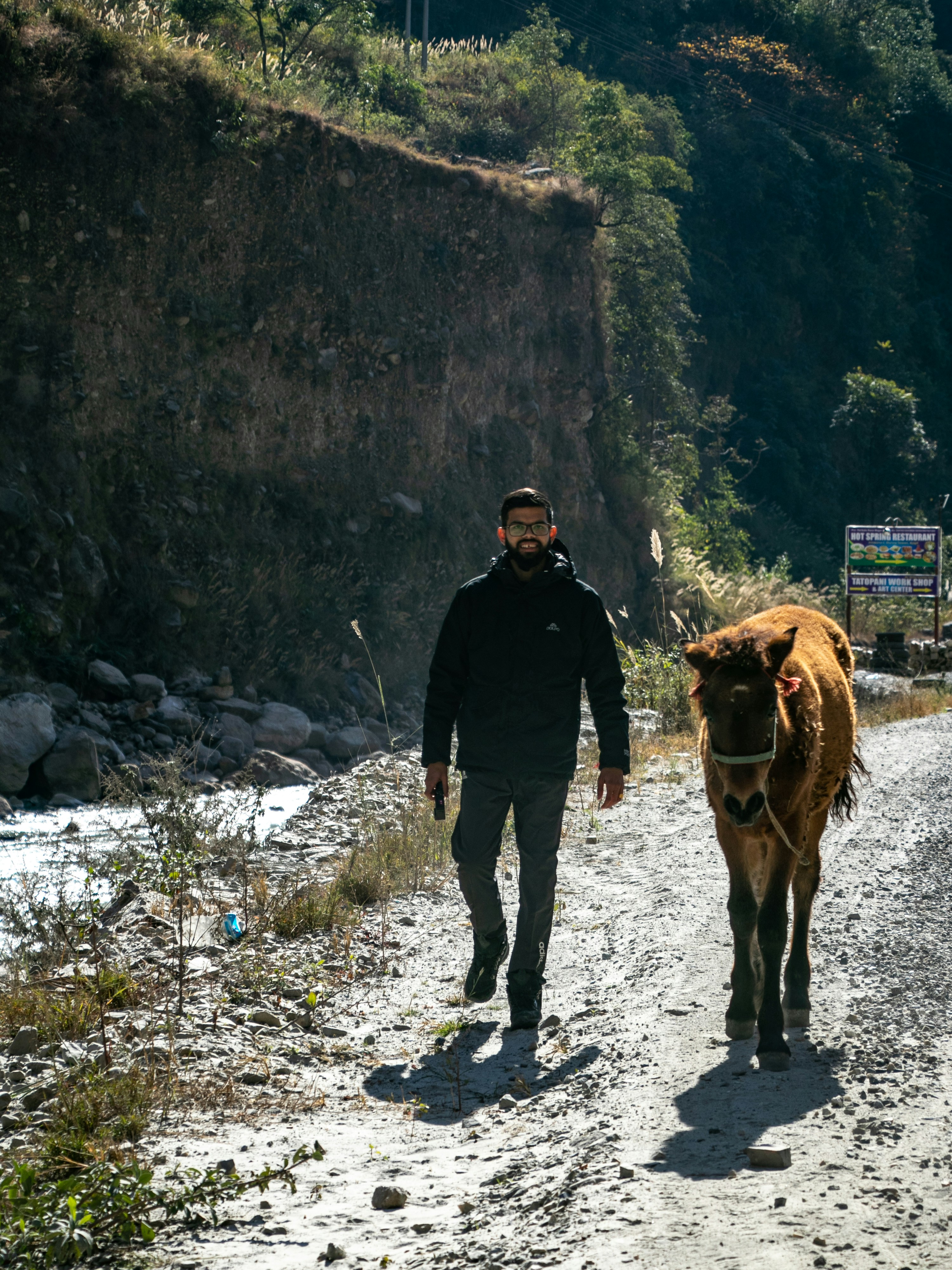 A man walking a horse down a dirt road