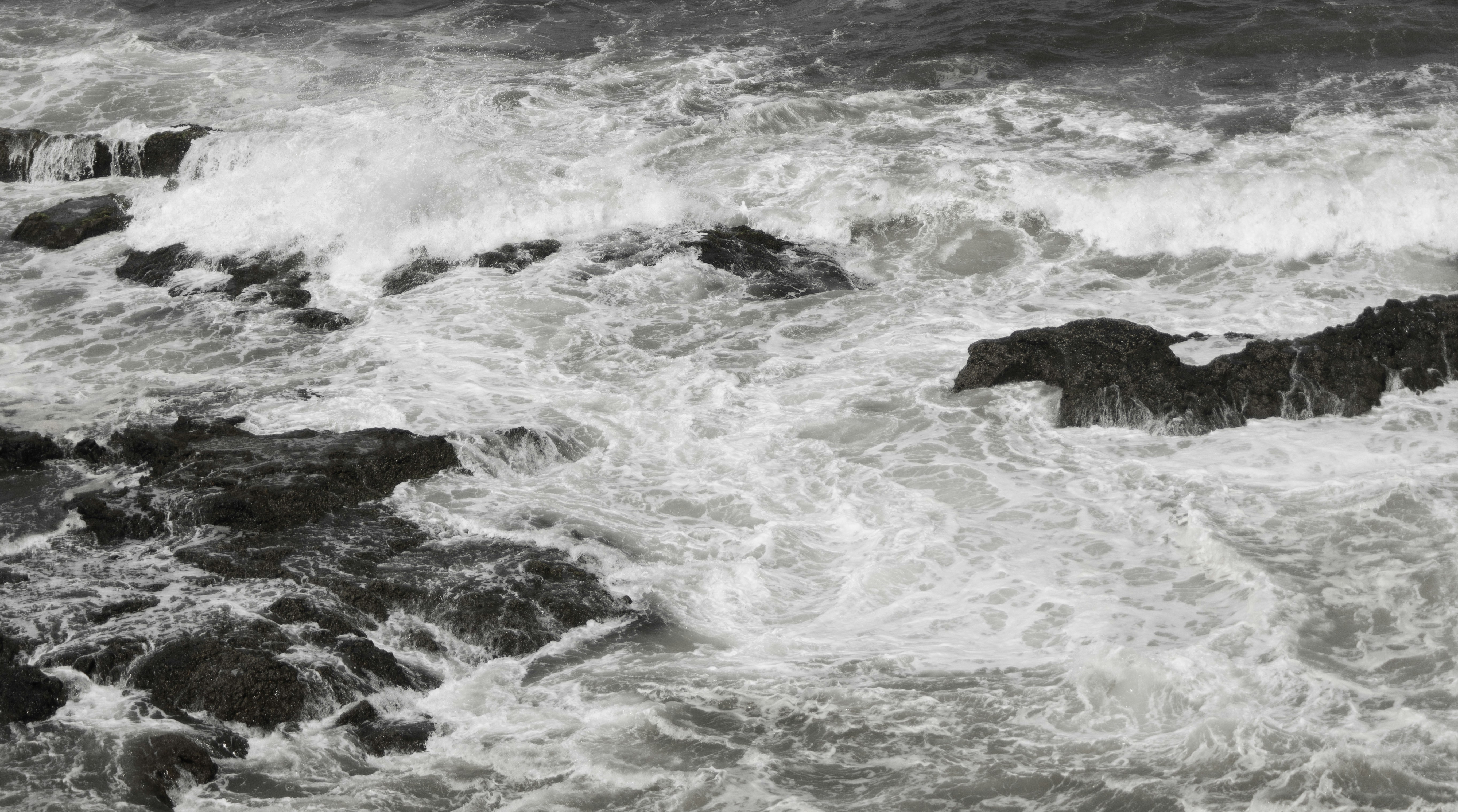 A black and white photo of waves crashing on rocks
