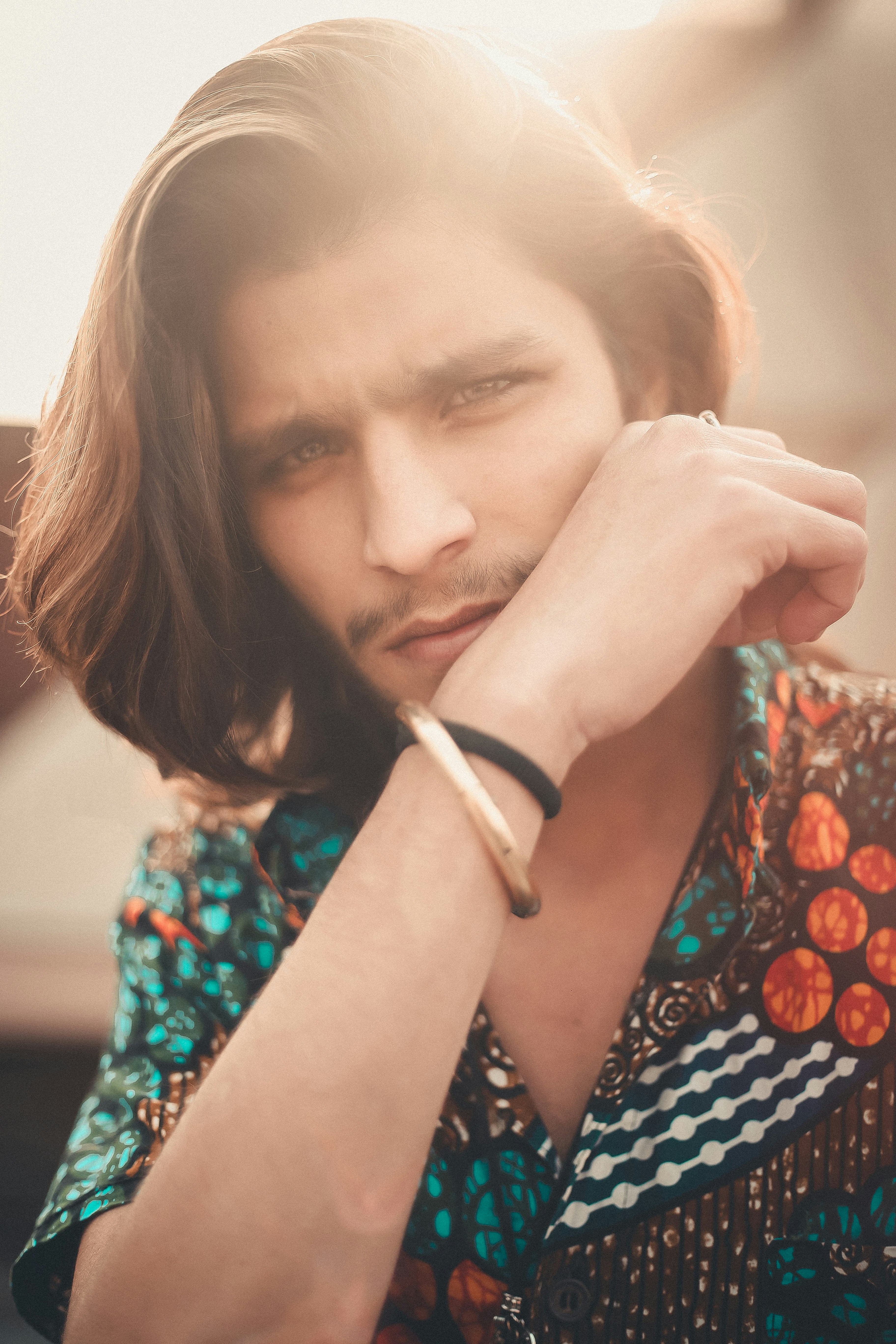 A man with long hair wearing a colorful shirt
