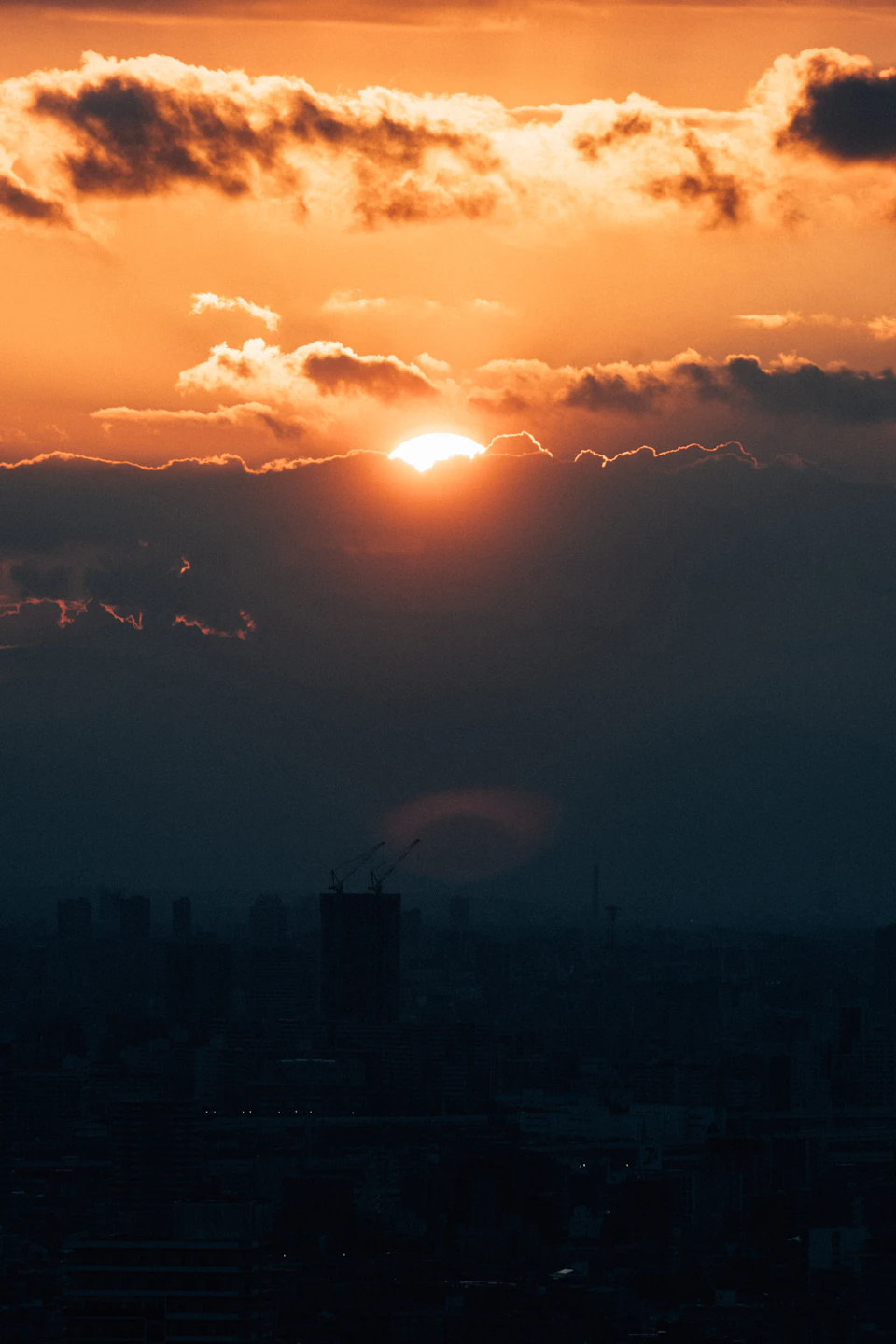 Breathtaking sunset over a cityscape with large cloud formation casting an orange glow across sky