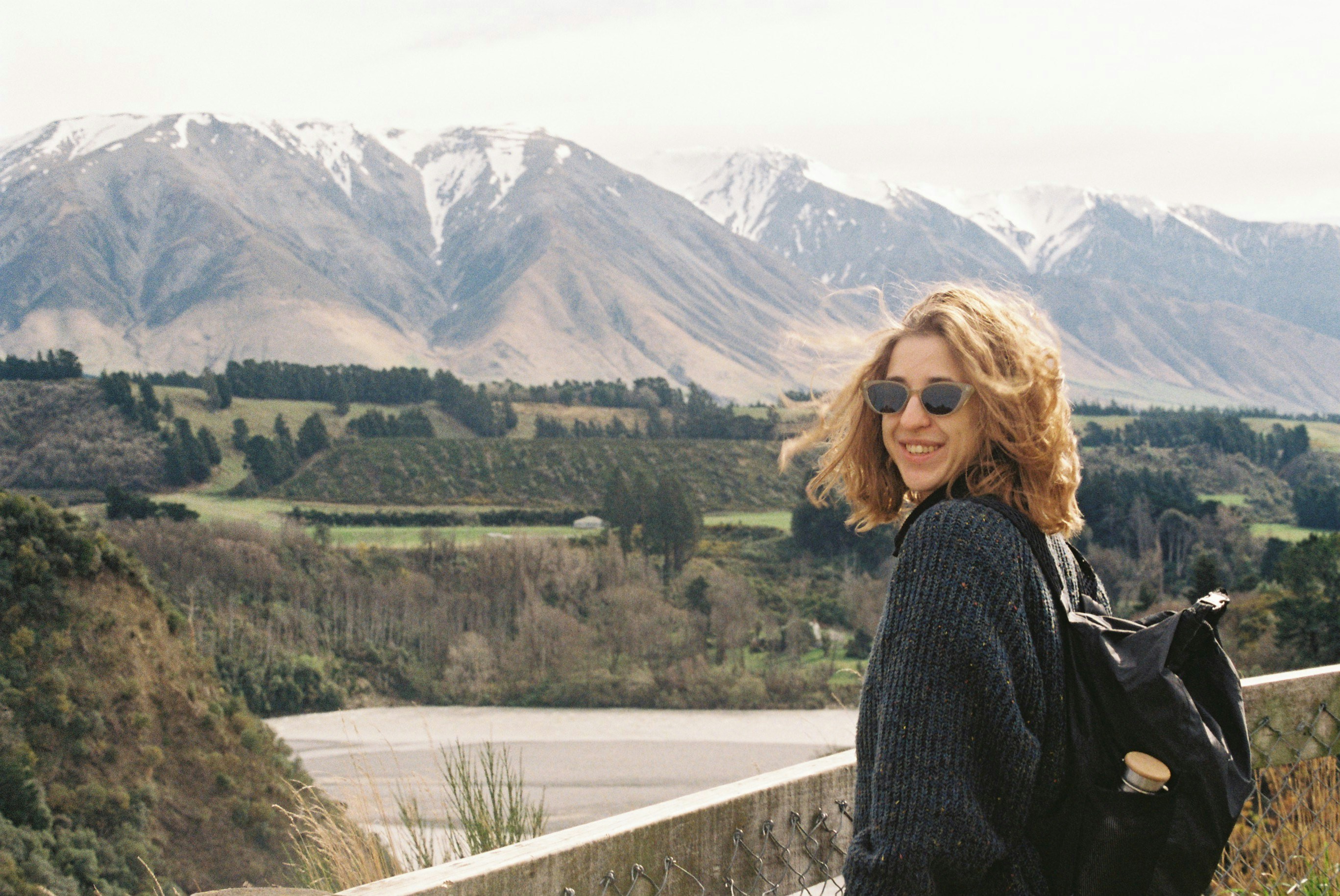 A woman standing on a bridge with mountains in the background