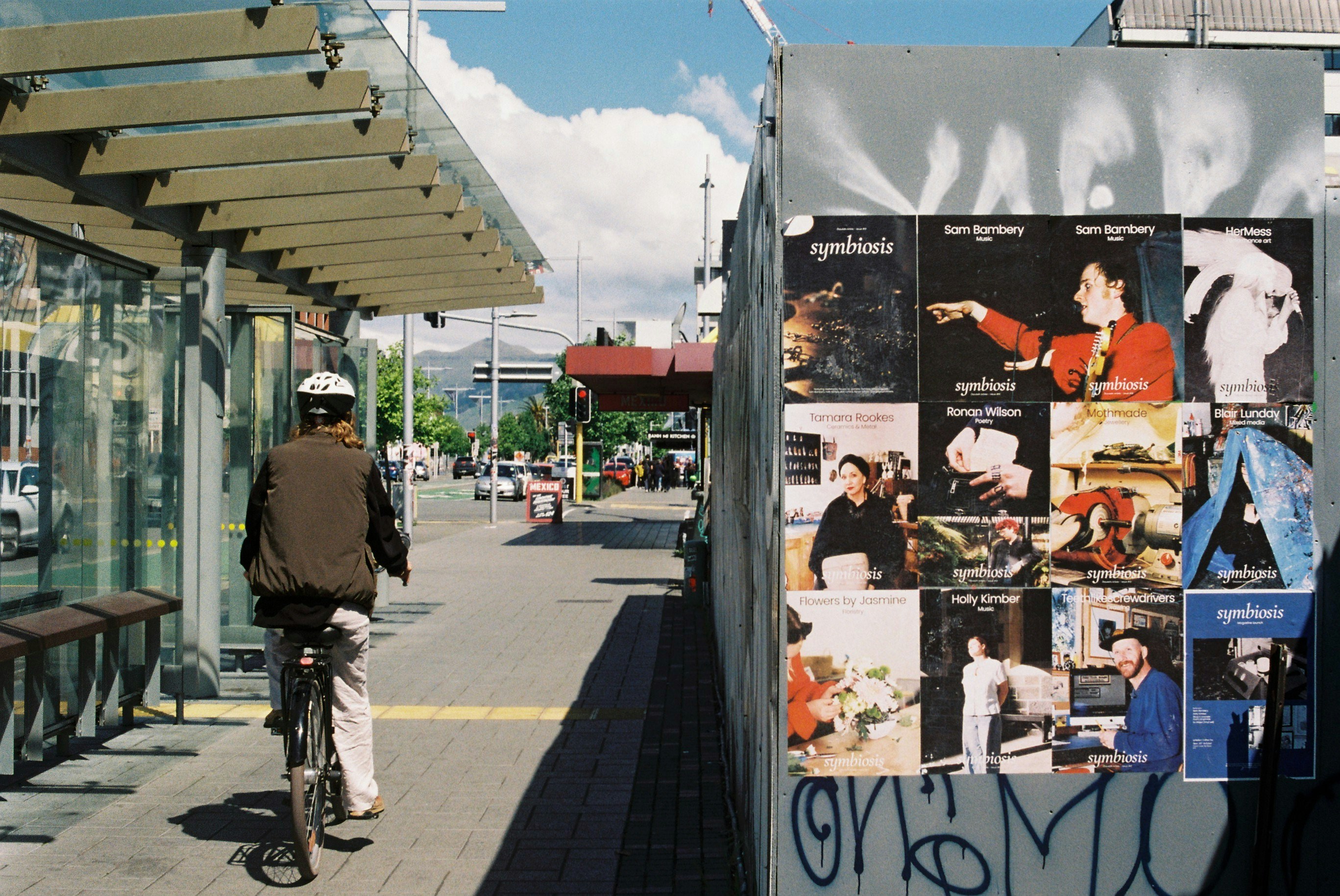 A man riding a bike down a street next to a bus stop