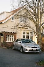 A silver car parked in front of a house