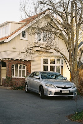 A silver car parked in front of a house