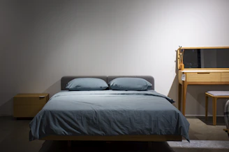 A bedroom with a bed, desk and mirror